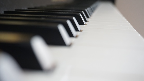 A close-up shot of the black and white keys of a grand piano, illuminated by natural light