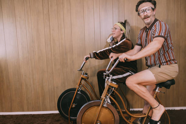 retro nineteen eighties aesthetic exercise bike couple - riding old old fashioned motion foto e immagini stock