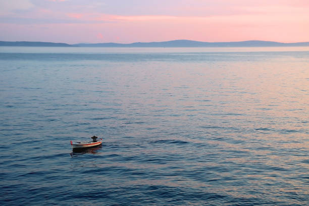 Beautiful sunset over the Adriatic Sea. Small old fashioned fishing boat at the sea.