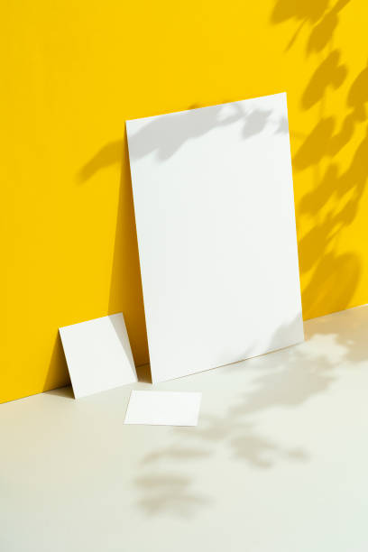 istock White textured paper  mockup set on yellow background with floral shadows. 1502564214