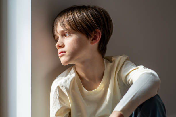 istock Sad boy orphan child sitting on windowsill at home, kid feeling lonely 1502567142