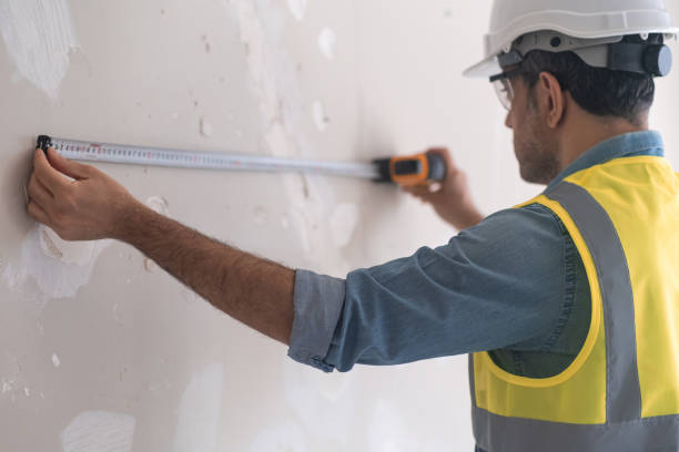 istock Focused engineer in protective helmet measuring shabby wall with tape-line 1502567778