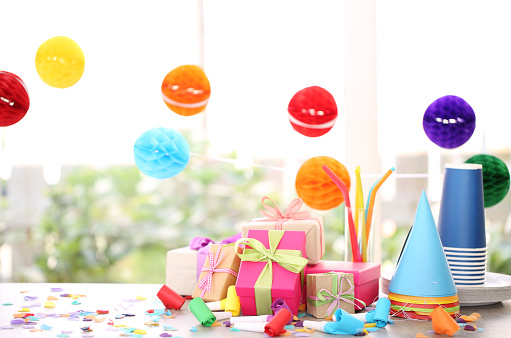 Colorful serpentine streamers, balloons and confetti on pink wooden table