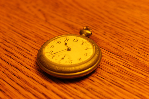 Close up of an antique manual wind-up pocket watch on a wooden table