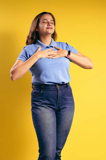 ritratto di una donna brasiliana, che indossa una polo e jeans, con entrambe le mani appoggiate sul petto, grata, gli occhi chiusi - belém - pará - brasile - polo shirt flash foto e immagini stock