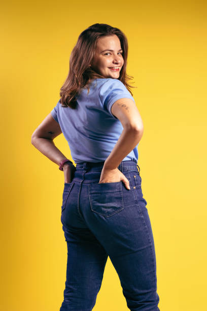 ritratto di una donna brasiliana, che indossa una polo e jeans, parzialmente con le spalle alla macchina fotografica, con le mani nella tasca posteriore e sorridente - belém - pará - brasile - polo shirt flash foto e immagini stock