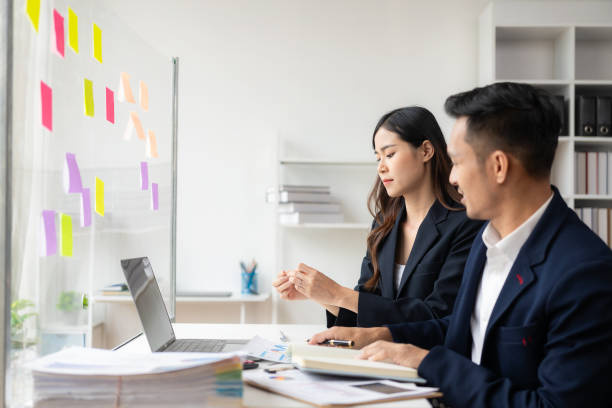 istock Smart and professional male manager working with his female assistant. check financial reports Analyze financial data with graph papers and laptop with desk. 1502629533