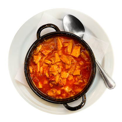 Dish of Spanish cuisine. Spicy stewed tripe callos in salsa with vegetables, garbanzo beans, smoked bacon and chorizo sausage served as main course. Isolated over white background