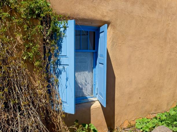 Blue shuttered window and adobe at San Francisco de Asis Catholic church.