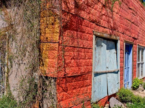 Taos, New Mexico - USA, May 12, 2023. Red tin siding of weathered building next to San Francisco de Asis Catholic Church.