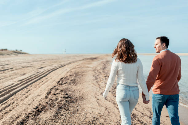 istock Beautiful couple holding hands and walking on the beach 1502665319