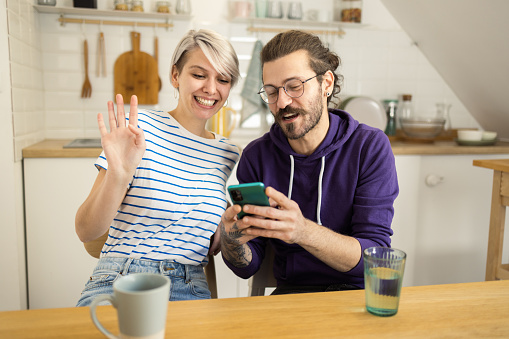 Portrait of a young couple relaxing at home and using a smartphone