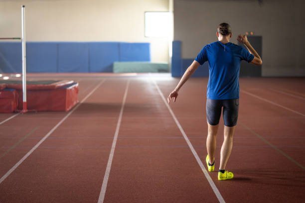 Young athlete practicing javelin-throwing technique on sports field with focus and precision. Open area and stadium backdrop create a dedicated training environment