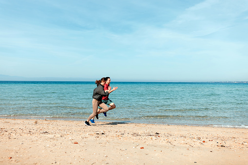 Active man and woman running on the beach