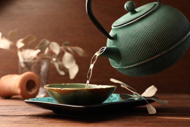 istock Pouring freshly brewed tea from teapot into cup on wooden table. Traditional ceremony 1502697702