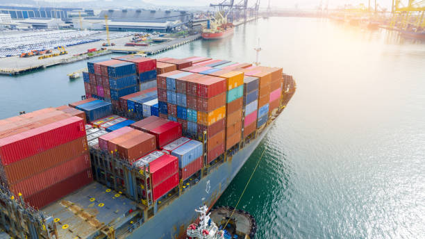 istock Tugboat pull container cargo ship vessel to cargo international container yard port concept shipping by sea. Freight shipping Cargo container box to customs Port. 1502702825