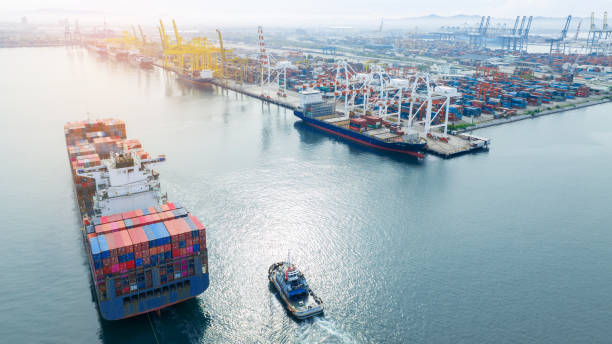 istock Tugboat pull container cargo ship vessel to cargo international container yard port concept shipping by sea. Freight shipping Cargo container box to customs Port. 1502702867