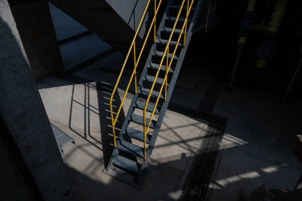 Side view at the yellow metal railing banister or handrail of the metal stairway with background of industrial working place.