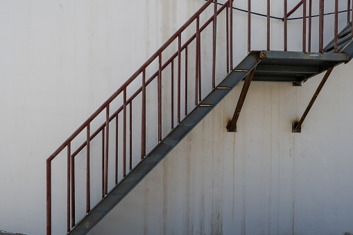 Handrails on the side of gray plaster wall along the large stone tiled staircase. Background for copy space.