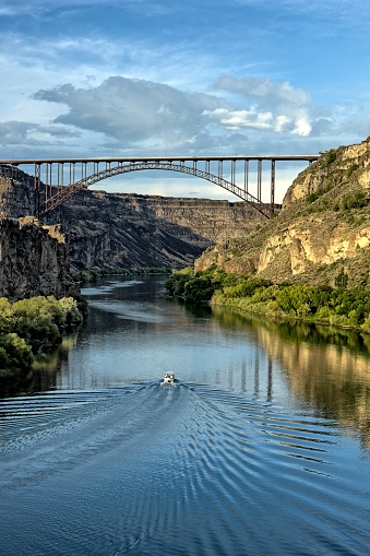 A boat cruises on the Sname River approaching the Perine Bridge in Twin Falls, Idaho.