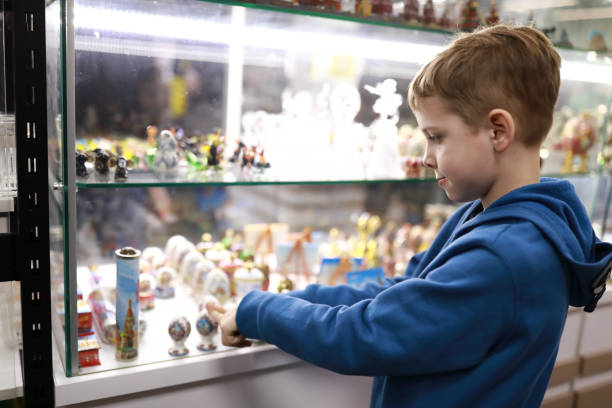 мальчик выбирает сувенир в витрине магазина - market market stall shopping people стоковые фото и изображения