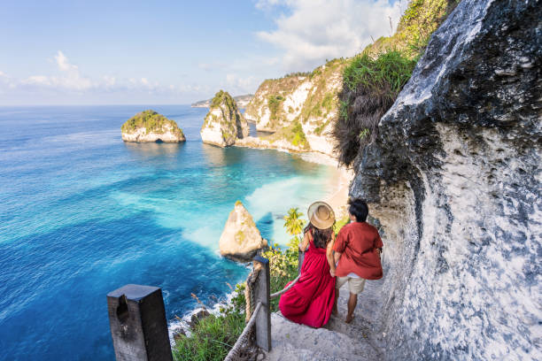 Young couple traveler relaxing and enjoying the beautiful view at diamond beach in Nusa Penida island, Bali stock photo