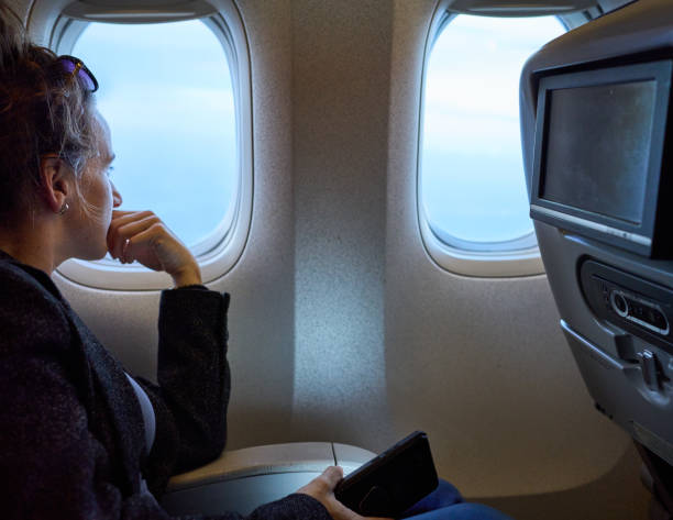 mujer viajera en el avión mirando por la ventana - silla al lado de la ventana fotografías e imágenes de stock
