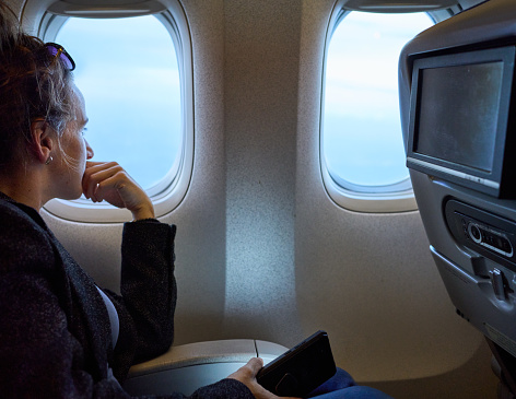 Side view of a woman traveling in plane and looking out of the window