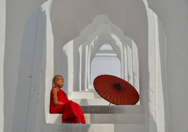 Young Buddhist monks sitting on the temple and looking at the view of ancient Bagan, Myanmar (Burma)