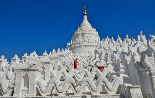 View of the white temple with a Buddhist novice monk in sunny day.