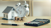 Investor of real estate.Calculator and pen with wooden home model and coins stack and clock. Property investment and house mortgage financial concept. fund finance and interest rate home loan.