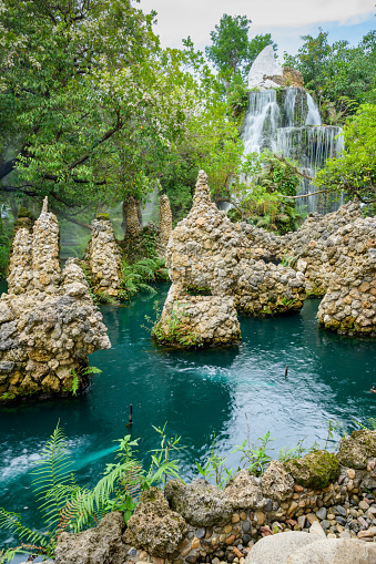 Small waterfall and green pond in shady garden, Chiang Mai province.