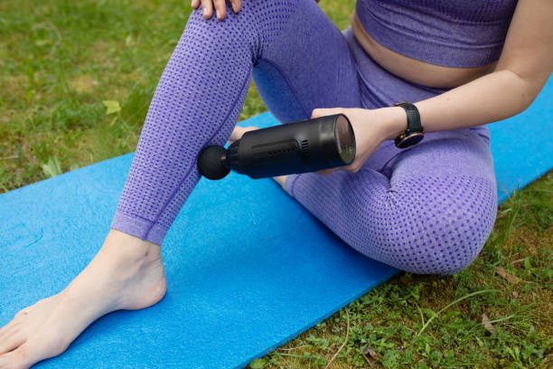 Massage of women's legs with a shock massage device. Self-massage to restore fascia muscles. Massage of women's legs with a shock massage device. Shock self-massage to restore fascia muscles. arm hammer stock pictures, royalty-free photos & images