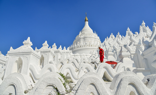 A Buddhist novice monk playing on steps of the white temple.