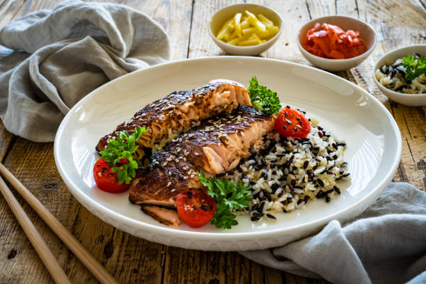 istock Seared teriyaki salmon steak with black and white rice on wooden table 1502782948