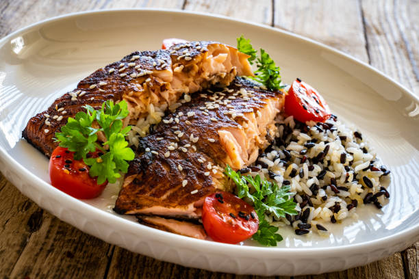 istock Seared teriyaki salmon steak with black and white rice on wooden table 1502782963