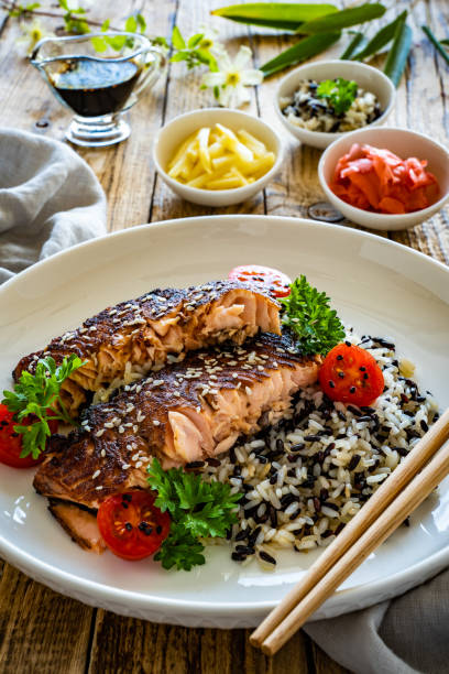 istock Seared teriyaki salmon steak with black and white rice on wooden table 1502782990