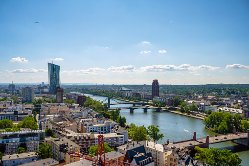 panoramic view over the roofs of Frankfurt city alongside the river with EZB tower in the background and historic town in the foreground under blue sky