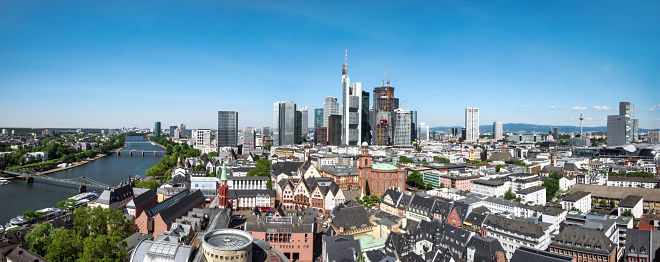 panoramic view over the roofs of Frankfurt city with modern skyline in the background and historic town in the foreground under blue sky, stitched image