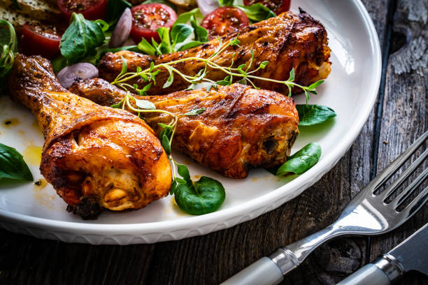 istock Grilled chicken drumsticks with chips and greens on wooden table 1502785167
