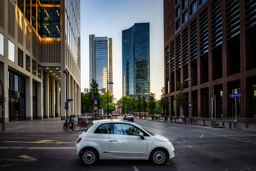 car passing crossroad in modern bank district in Frankfurt at sunset hour