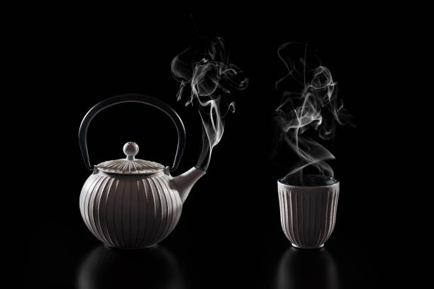 istock Steaming teapot and cup of tea on a dark background 1502787556