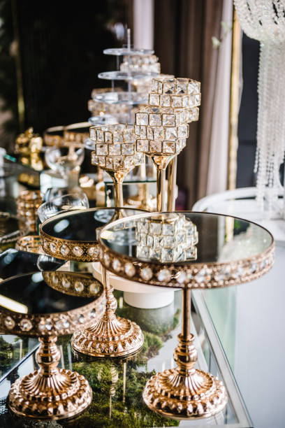 istock Table with plates stands for candy bar, catering. Decorating an event in restaurant. Wedding hall with atmospheric decor. Golden geometric decorative elements decor. Luxury reception. Setting, setup. 1502787720