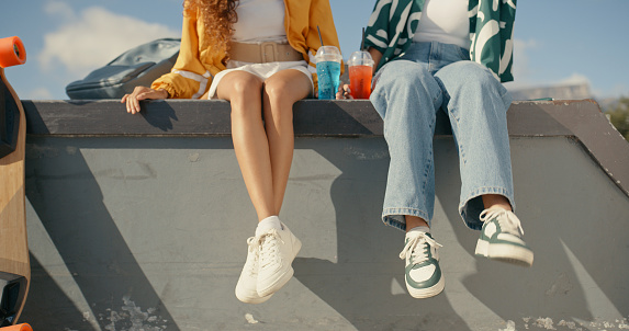 Relax, drink and shoes with friends at skate park for bonding, happiness and hipster. Summer, closeup and teenager with people and skateboard in outdoors for skating, fitness and training together