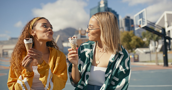 Friends, women and eating ice cream in city, spending time together outdoor with dessert and summer. Friendship date at urban park, gelato cone and luxury snack, female people happy and care free