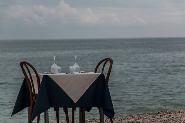 istock Wooden table with glasses and chairs on a beachfront, overlooking the serene ocean 1502789151