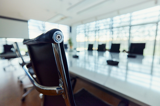 Close up of a black office chair with metal details at conference table in meeting room.