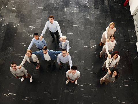 High angle view of large group of business colleagues forming an AI letters for artificial intelligence and looking at camera. Copy space.