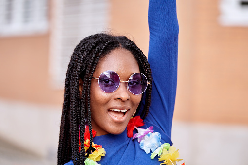 African American woman wearing a flower necklace and sunglasses while partying outdoors.