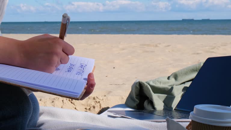 Young student study with notebook on beach next to sea ocean view. Writing gratitude journal self reflection self discovery self discovery, journal, self reflection, creative writing, self growth, personal developmentDrinking coffee and eat croissants. O